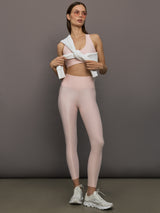 Model wears a pair of high rise baby pink sleek liquidy shine leggings. 