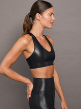 Model wears a black v-neck sports bra in a liquid metallic shine finish.