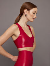 Model wears a bright red shiny, liquidlike sports bra with a v neck. 