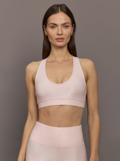 Model wears a v neck baby pink bra in a liquidy takara shine finish. 