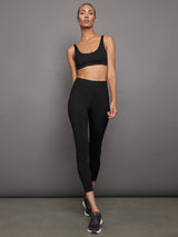 Full outfit view of ribbed black scoop neck bra with matching leggings and sneakers.