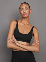 Model wearing ribbed scoop neck sports bra in black, front view.
