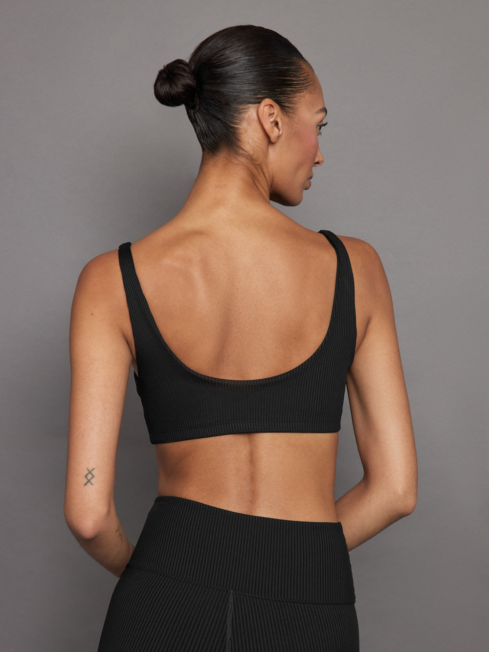 Back view of ribbed black scoop neck sports bra showing low scoop design.