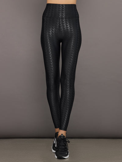 Model wears a pair of high waisted black houndstooth print leggings. 