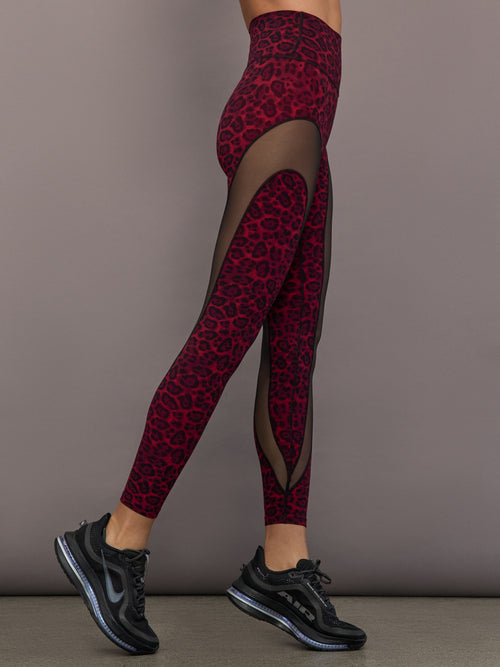 Model is wearing Melt sheer spliced leggings in red leopard, side view mesh panel detail.