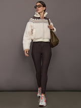 Model in dark brown high-rise leggings with drawstring waist and pockets, paired with a cream sherpa zip-up jacket, oversized sunglasses, brown shoulder bag, and sneakers, front view.