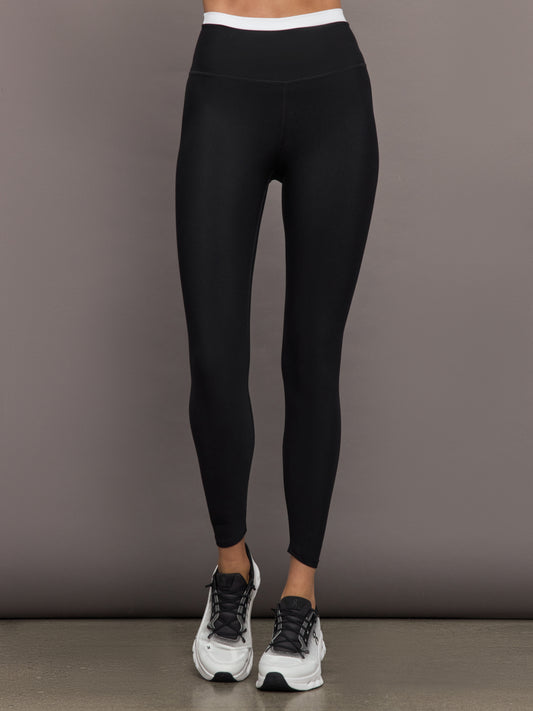 Model wears black full-length leggings with a high-rise, wide waistband with a contrasting white.