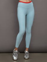 Model wears a light blue performance legging with a red waistline. 