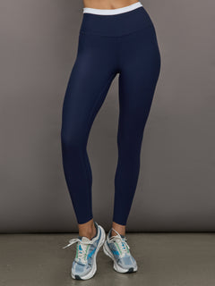 Model wears a buttery soft high waisted navy legging with thin white waistband. 