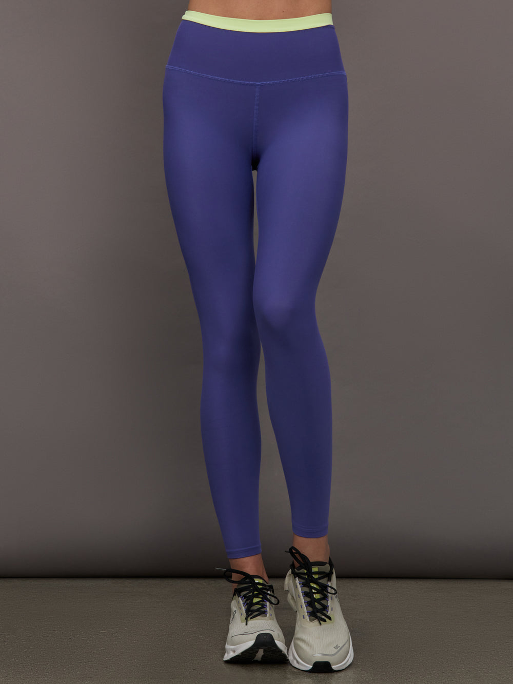 Model wearing blue leggings with bright green contrast on the waist