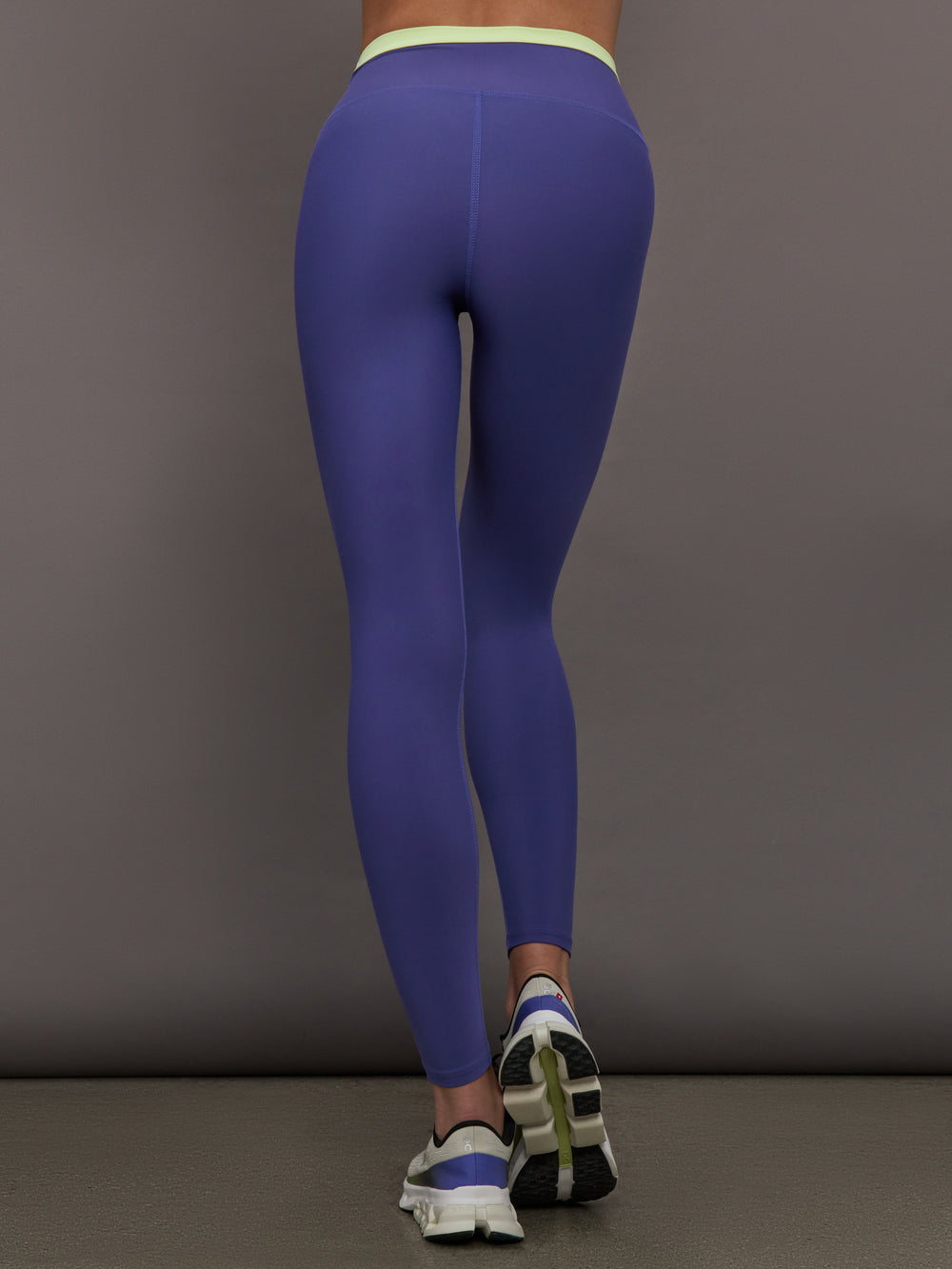 Model wearing blue leggings with bright green contrast on the waist