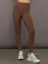 Model wearing high-rise ribbed leggings in cocoa brown, front view with fitted waistband and ankle-length design.