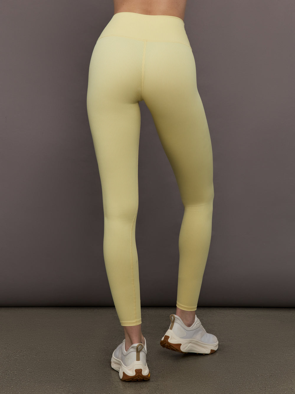 Model is wearing Melt Rib High Rise Legging in Banana, back view.