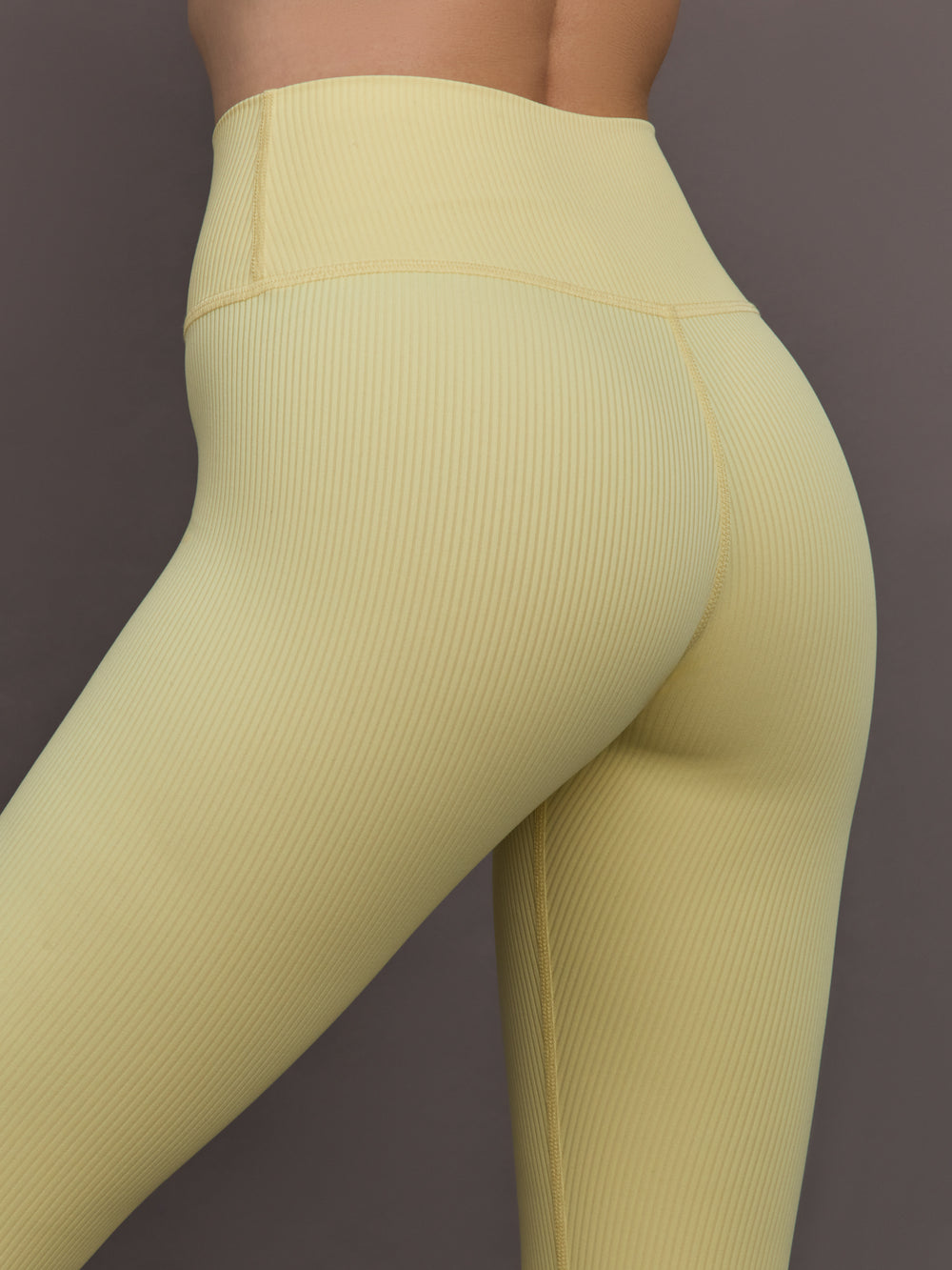 Model is wearing Melt Rib High Rise Legging in Banana, side close-up detail.