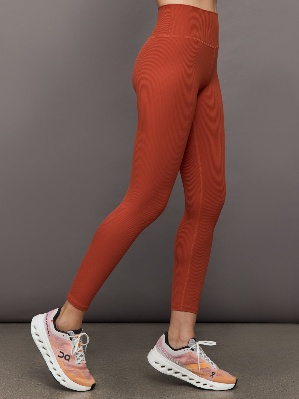 Side profile of ribbed terracotta high-rise leggings on model.