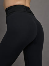 Model wears a pair of high waisted black full length leggings with ruching around the waistline. 