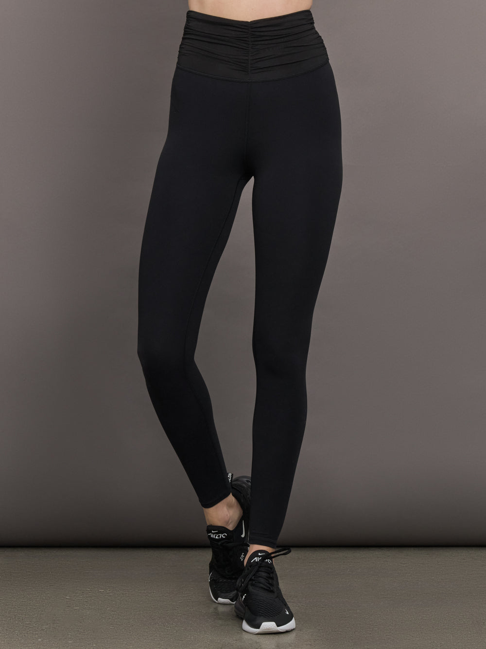 Model wears the Melt and Mesh Ruched Legging in Black, with ruched detailing at the waistband and breathable mesh for a sculpted look.