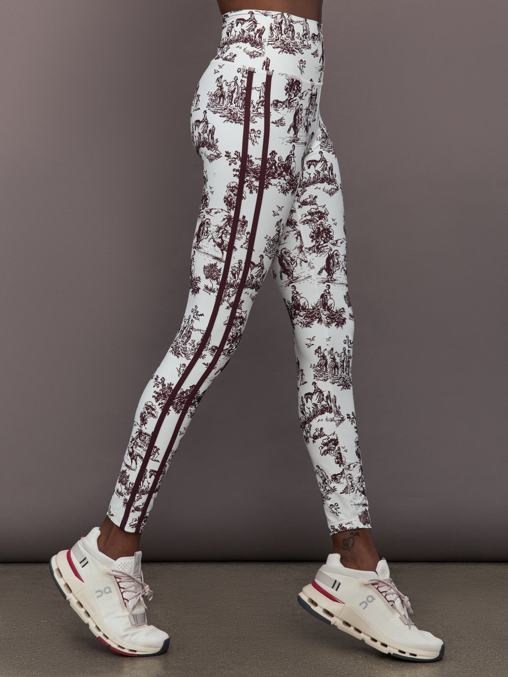 Model wears a pair of white leggings with burgundy toile print. 