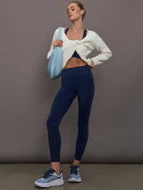 Full body view of model in Diamond Compression High Rise Pocket Legging Navy styled with white cardigan and blue bag.