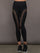 Model wears a pair of black high waisted leggings with laser cutouts along thighs. 