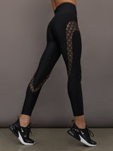 Model wears a pair of black high waisted leggings with laser cutouts along thighs. 