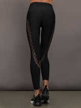 Model wears a pair of black high waisted leggings with laser cutouts along thighs. 