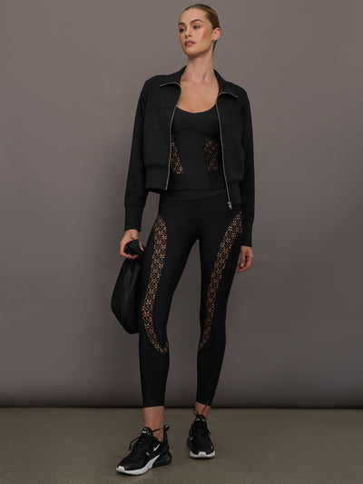 Model wears a pair of black high waisted leggings with laser cutouts along thighs. 