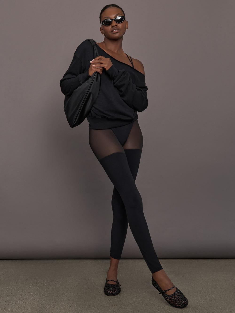 Model wears black leggings with sheer thighs and high cut underwear silhouette. 