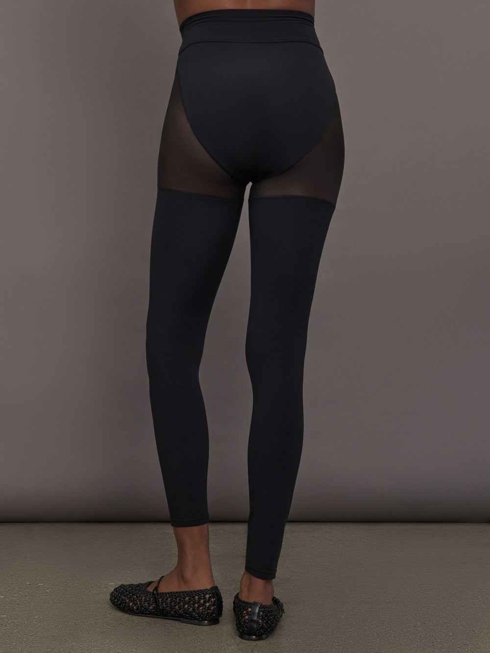 Model wears black leggings with sheer thighs and high cut underwear silhouette. 
