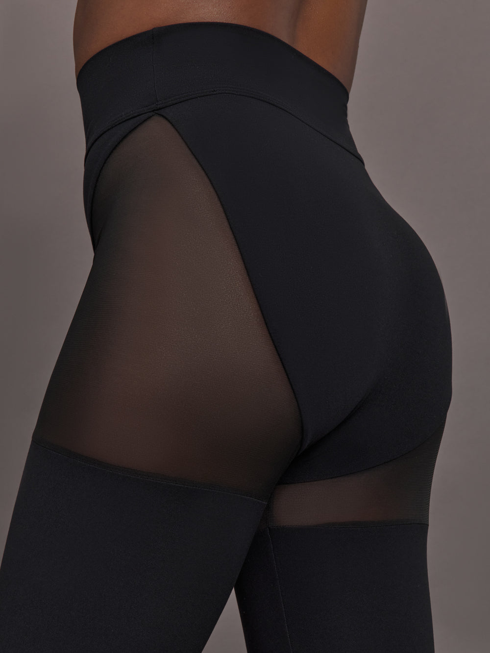 Model wears black leggings with sheer thighs and high cut underwear silhouette. 