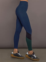 Model is wearing Melt High-Waisted Colorblock Legging in Navy, Black, and Forest, side view.