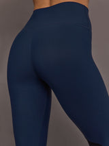 Model is wearing Melt High-Waisted Colorblock Legging in Navy, Black, and Forest, close-up of waistband and fabric.
