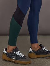 Model is wearing Melt High-Waisted Colorblock Legging in Navy, Black, and Forest, close-up of colorblock leg panel.