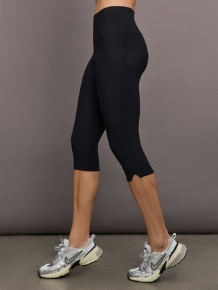 Model is wearing High Rise Capri Legging in Melt Black, side view highlighting high-rise waistband and cropped length.