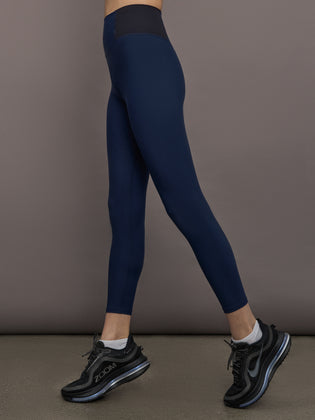 Model is wearing Seamed Melt Legging in Navy/Black, side profile view highlighting ribbed high-rise waistband.