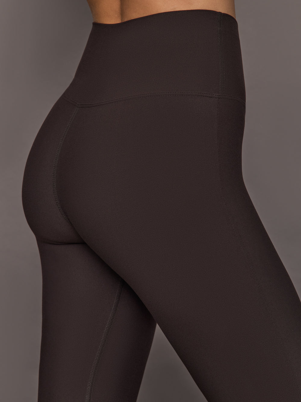 Back shot of Brown flared leggings perfect for yoga or pilates worn by a person on a gray background