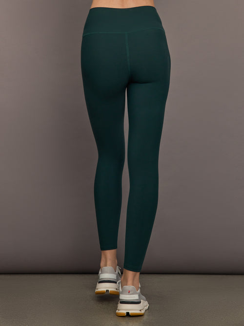 Model is wearing the High Rise Legging in Forest, back view.
