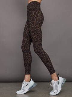 Side view of Melt High-Rise Leopard Print Legging paired with Nike sneakers.