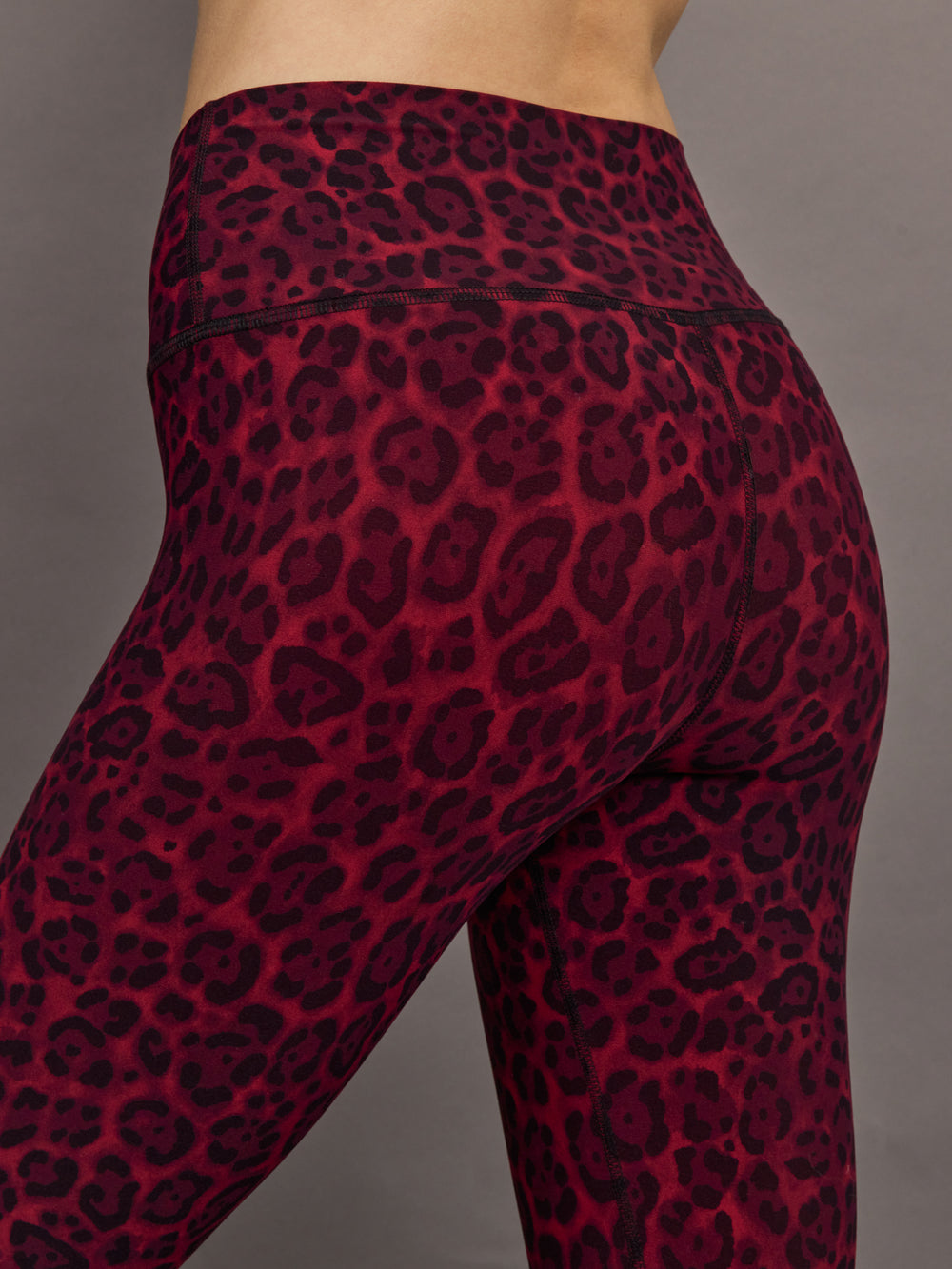 Waistband and hip seam detail of Melt leggings in red leopard pattern, close-up back view.