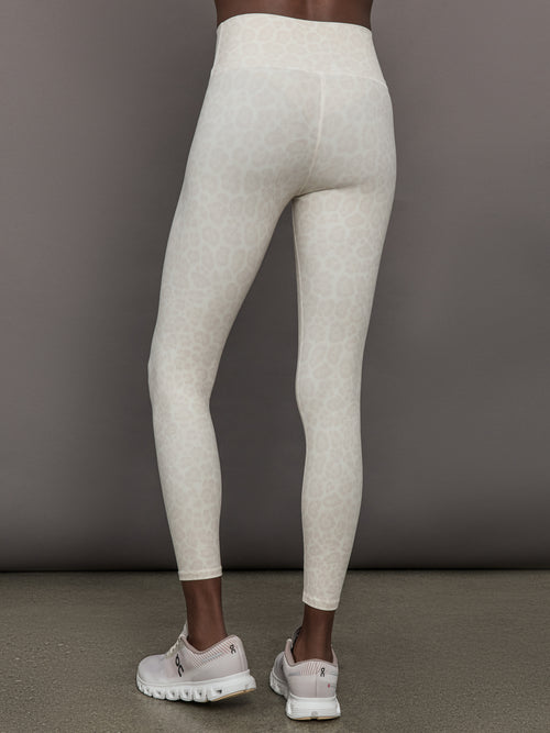 Model wears a pair of buttery soft, high waisted athleisure leggings in a snow leopard colored print. 