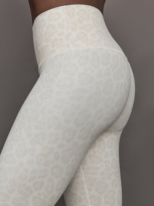 Model wears a pair of buttery soft, high waisted athleisure leggings in a snow leopard colored print. 