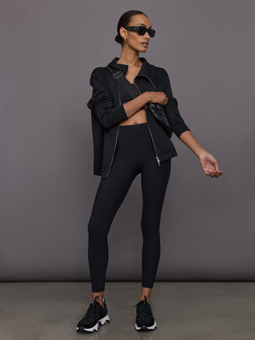 Full body view of model styled in Melt Strappy Bra in Black with matching leggings and jacket.
