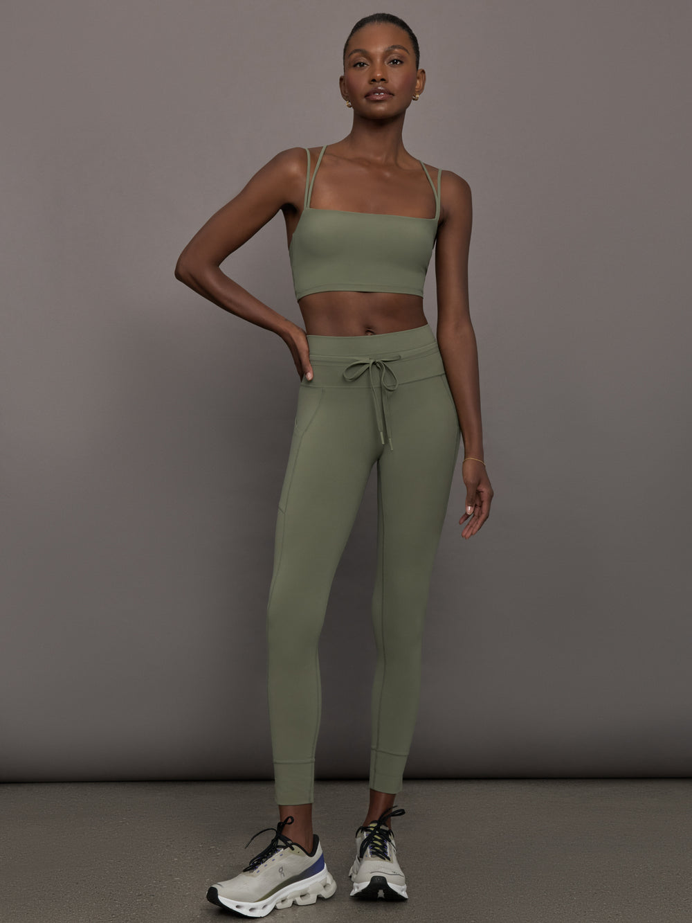 Model wears a buttery soft sports bra in army green with double straps and cross back design. 