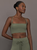 Model wears a buttery soft sports bra in army green with double straps and cross back design. 