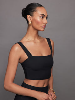 Side view of model wearing Melt Square Neck Bra Top Black with gold earrings.
