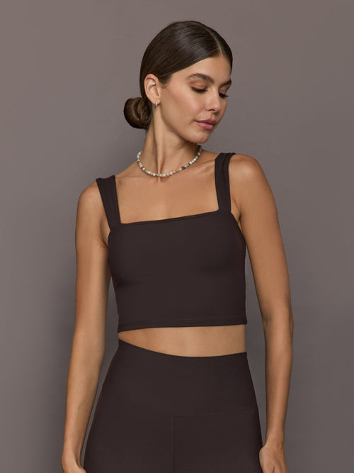 Model is wearing a dark brown square-neck cropped tank top with wide straps and a fitted silhouette, front view.