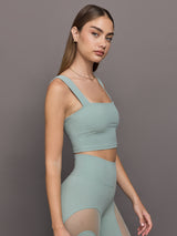 Model wears sage green bra top with a square neckline and wide shoulder straps.