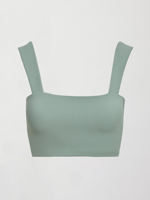 Model wears sage green bra top with a square neckline and wide shoulder straps.