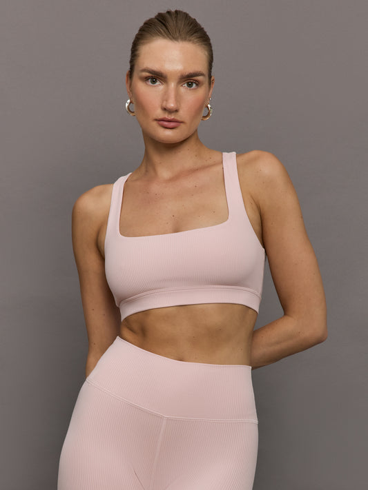 Model wearing a matching light pink racerback sports bra.