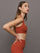 Model wears terracotta-colored racerback bra with a ribbed texture, square neckline, and wide straps that merge at the back.
